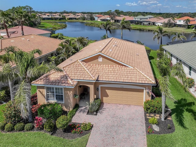 view of front of property featuring a garage, decorative driveway, a water view, and a residential view