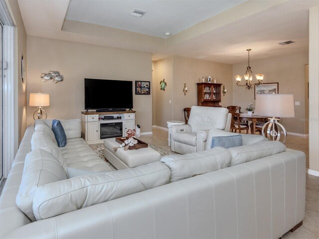 living room with a raised ceiling, visible vents, and baseboards