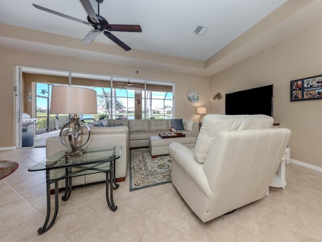 living area featuring a ceiling fan, visible vents, baseboards, and light tile patterned floors