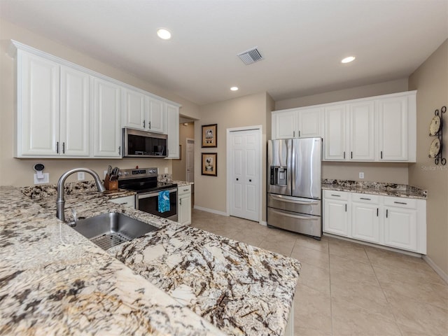 kitchen with light stone countertops, visible vents, stainless steel appliances, and a sink