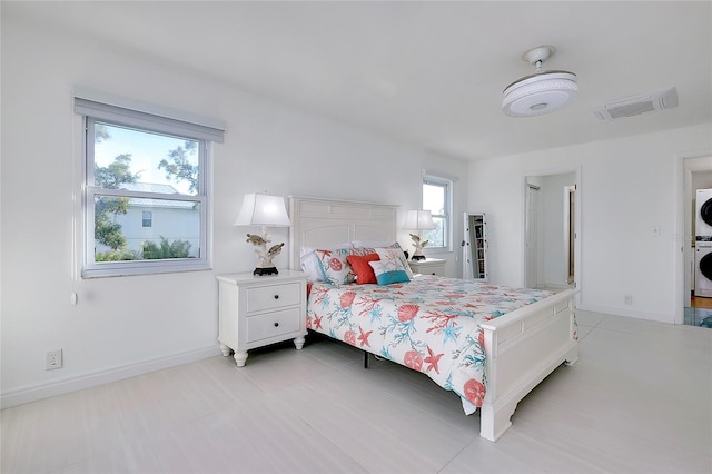 bedroom with stacked washer / dryer, visible vents, and baseboards