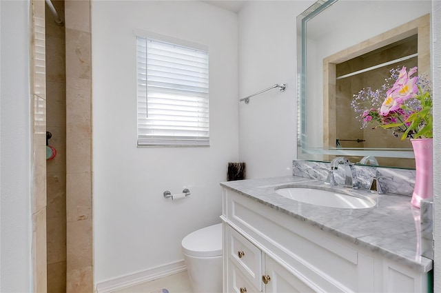 bathroom featuring baseboards, a tile shower, vanity, and toilet