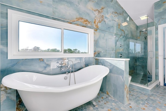 bathroom with a stall shower, a freestanding tub, and tile walls