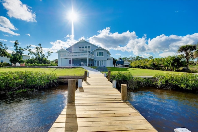 view of dock featuring a water view, a balcony, and a yard