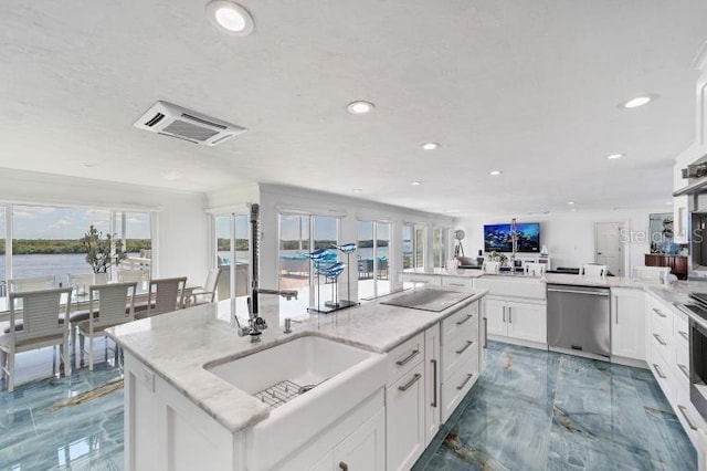 kitchen featuring light stone counters, marble finish floor, stainless steel dishwasher, white cabinetry, and an island with sink