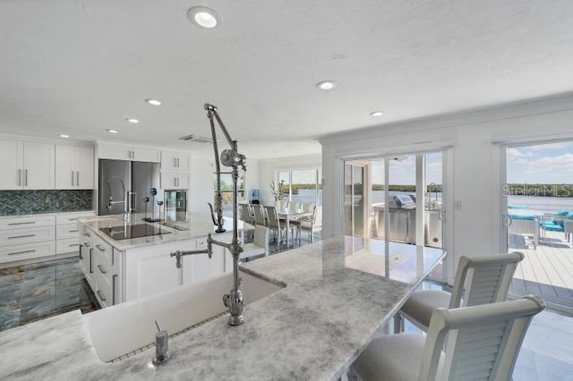 kitchen with a spacious island, stainless steel refrigerator, backsplash, and white cabinetry