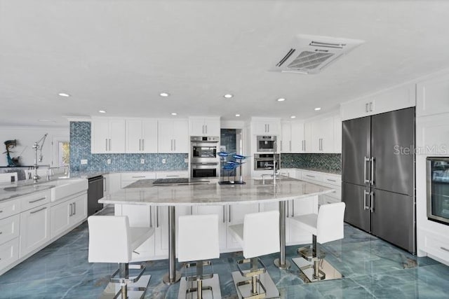 kitchen with appliances with stainless steel finishes, visible vents, a large island, and a kitchen bar