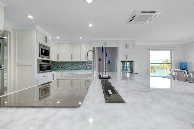 kitchen featuring visible vents, backsplash, appliances with stainless steel finishes, ornamental molding, and white cabinetry