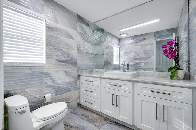 full bath with marble finish floor, tile walls, toilet, and vanity