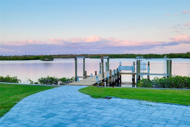 view of dock with a lawn, a water view, and boat lift