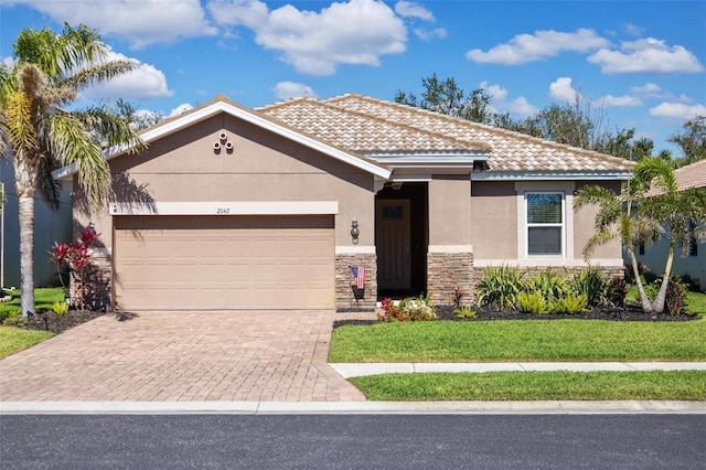 ranch-style house with an attached garage, stone siding, a tiled roof, decorative driveway, and stucco siding