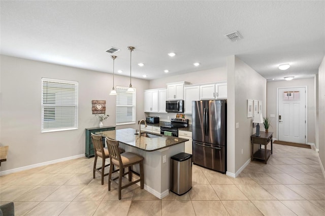 kitchen with an island with sink, visible vents, appliances with stainless steel finishes, and a sink