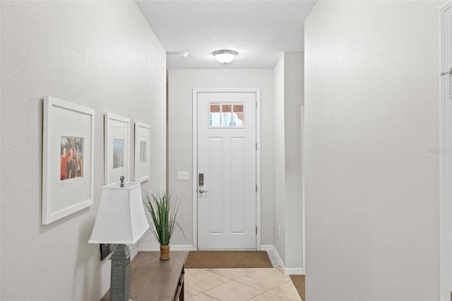 entrance foyer with light tile patterned floors, a textured ceiling, and baseboards