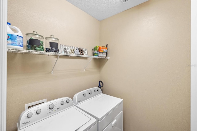 washroom featuring laundry area, a textured ceiling, and washing machine and clothes dryer