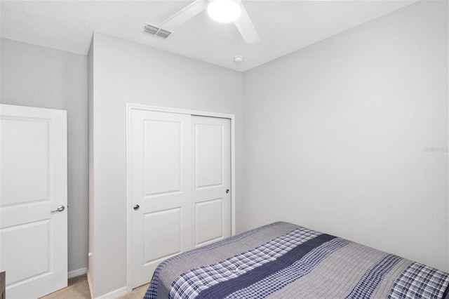 bedroom featuring ceiling fan, a closet, visible vents, and light colored carpet