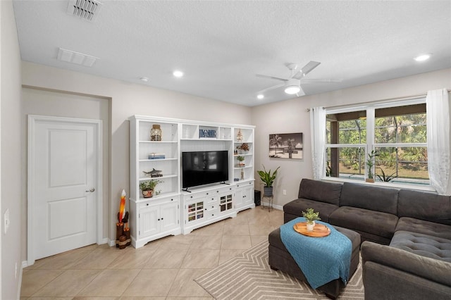 living area with light tile patterned floors, a textured ceiling, visible vents, and a ceiling fan