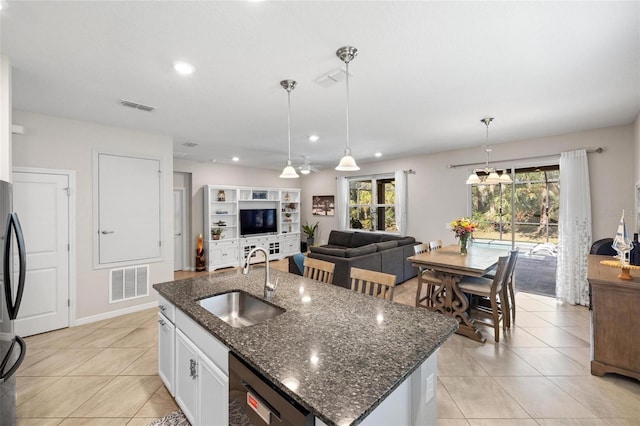 kitchen with dishwasher, a center island with sink, visible vents, and a sink