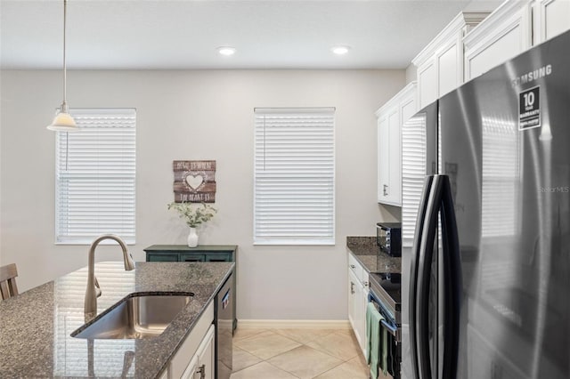 kitchen featuring light tile patterned floors, a sink, white cabinets, appliances with stainless steel finishes, and dark stone countertops