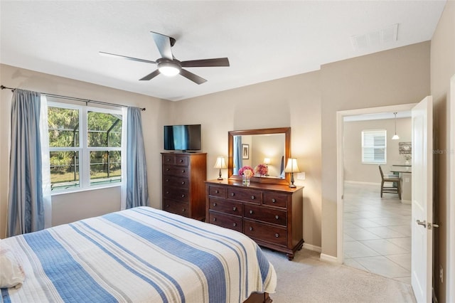 bedroom with light carpet, light tile patterned floors, baseboards, visible vents, and a ceiling fan