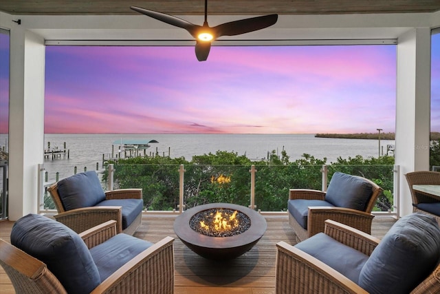 wooden deck featuring a dock, an outdoor living space with a fire pit, and a water view