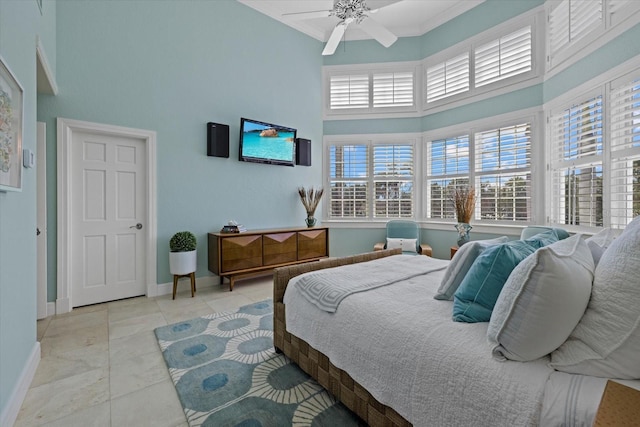 tiled bedroom with ceiling fan, a high ceiling, and baseboards