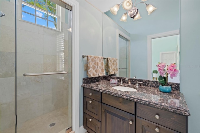 full bathroom featuring a stall shower, vanity, and a notable chandelier