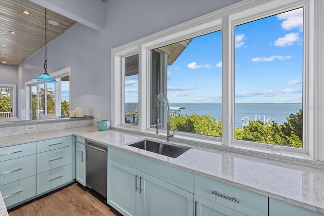 kitchen with dishwasher, wood finished floors, decorative light fixtures, a water view, and a sink