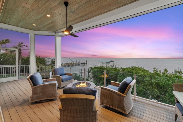 wooden terrace with a water view and a fire pit