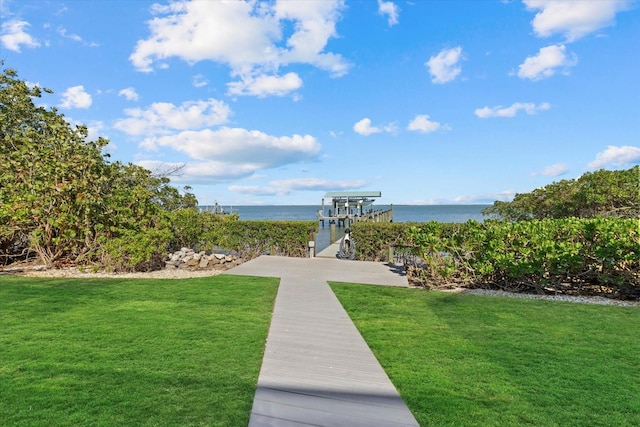 view of community featuring a water view, boat lift, and a yard