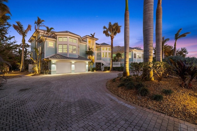 view of front of home with decorative driveway, an attached garage, and stairs