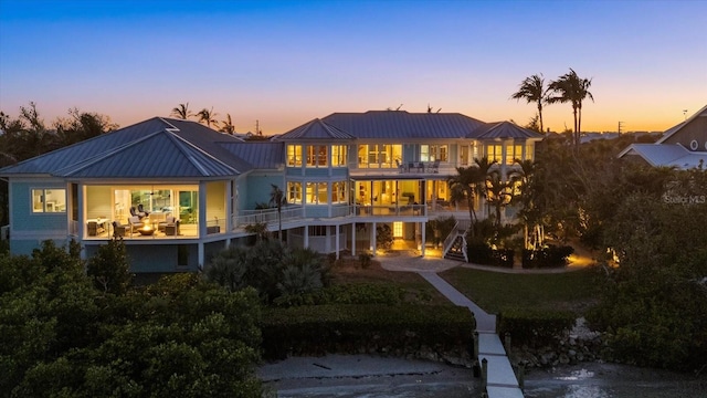 rear view of property featuring a standing seam roof, metal roof, and a balcony