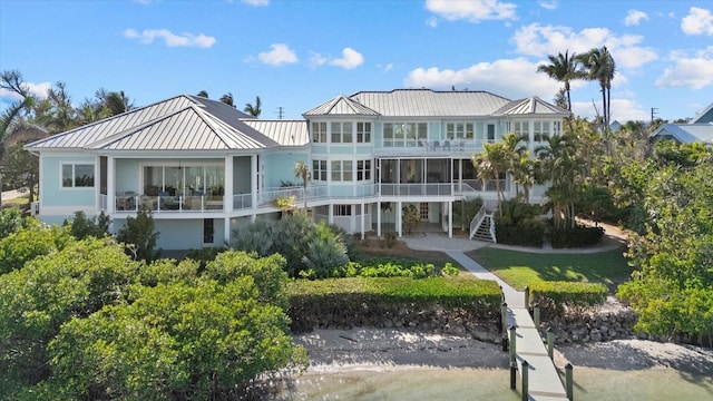 rear view of property featuring a standing seam roof, metal roof, a balcony, and stairs