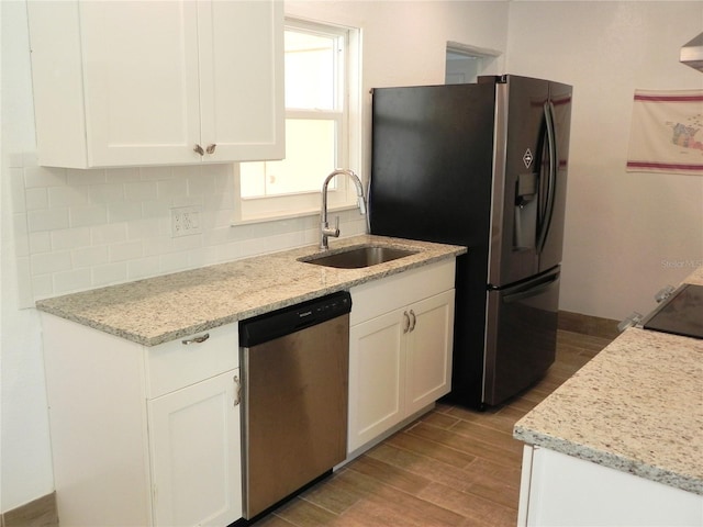 231 Redwood Rd, Venice, FL 34293 - kitchen with backsplash, appliances with stainless steel finishes, white cabinetry, a sink, and wood finished floors