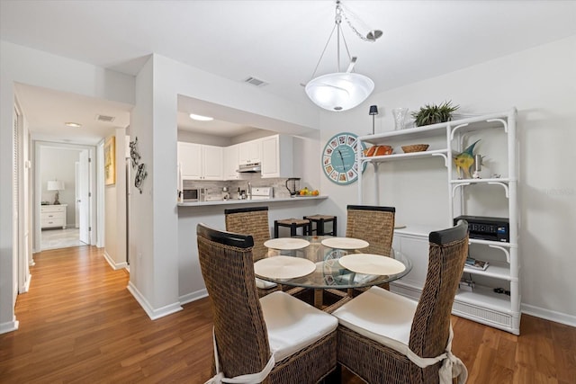 dining area with visible vents, baseboards, and wood finished floors