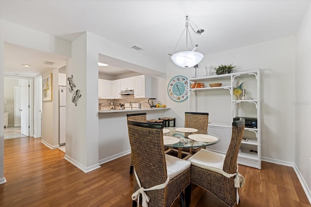 dining room featuring visible vents, baseboards, and wood finished floors