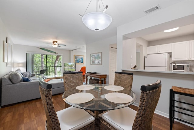 dining room with dark wood-type flooring, visible vents, baseboards, and a ceiling fan