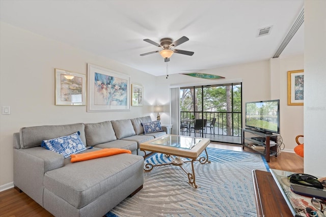 living room featuring a ceiling fan, wood finished floors, visible vents, and baseboards