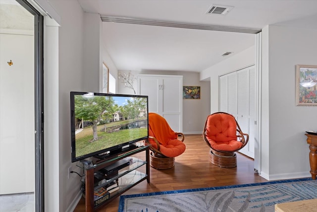 living area with baseboards, visible vents, and wood finished floors