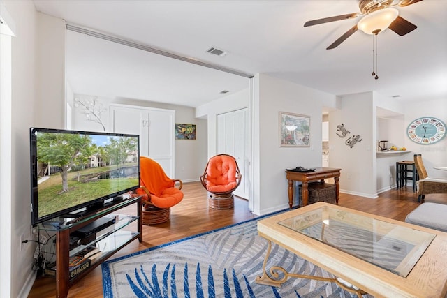 living room with visible vents, baseboards, and wood finished floors