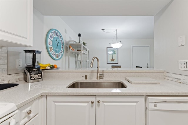 kitchen featuring backsplash, white cabinets, white dishwasher, a sink, and a peninsula