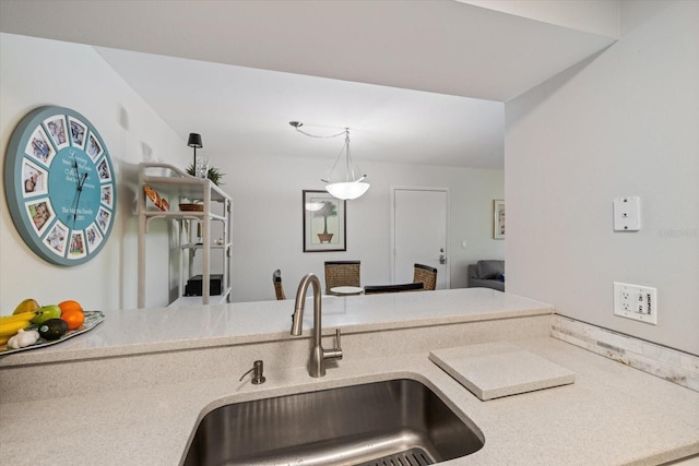 kitchen featuring light countertops, a sink, and hanging light fixtures