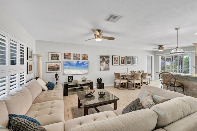 living area featuring a ceiling fan, light wood-style flooring, visible vents, and baseboards