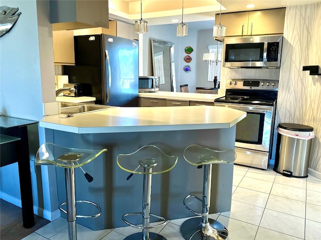 kitchen with light tile patterned floors, a peninsula, stainless steel appliances, light countertops, and a sink