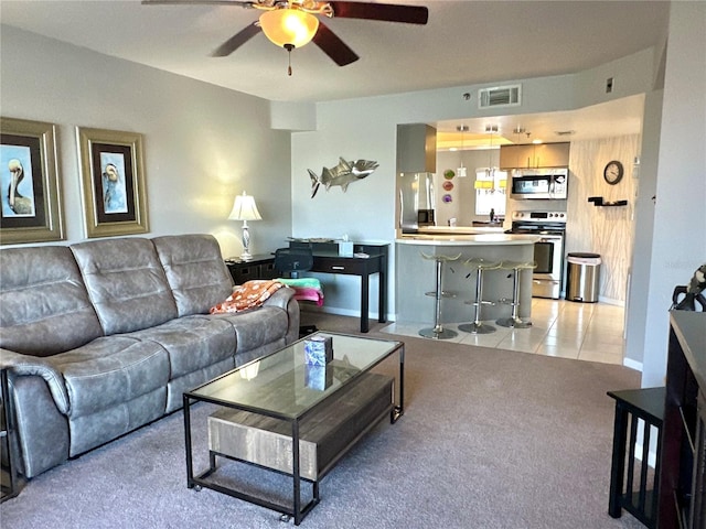 living room with light carpet, light tile patterned floors, ceiling fan, and visible vents