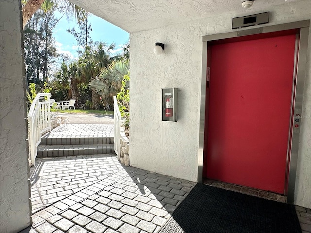 entrance to property featuring a patio, stucco siding, and elevator