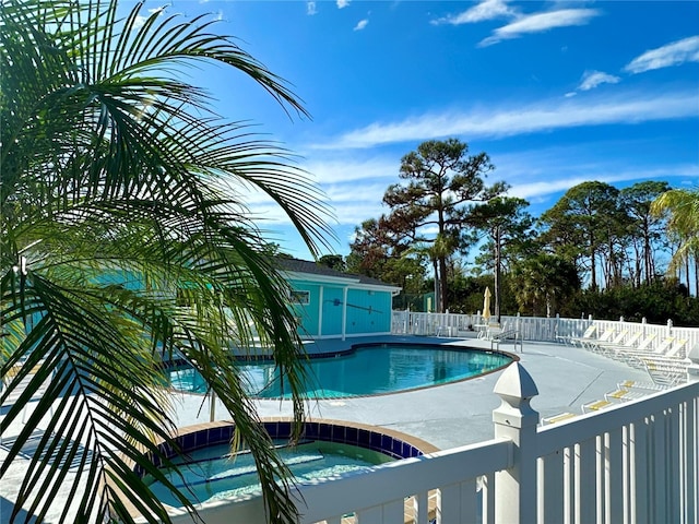 community pool with a patio area, a hot tub, and fence