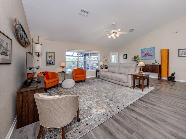 living room featuring lofted ceiling, visible vents, and wood finished floors