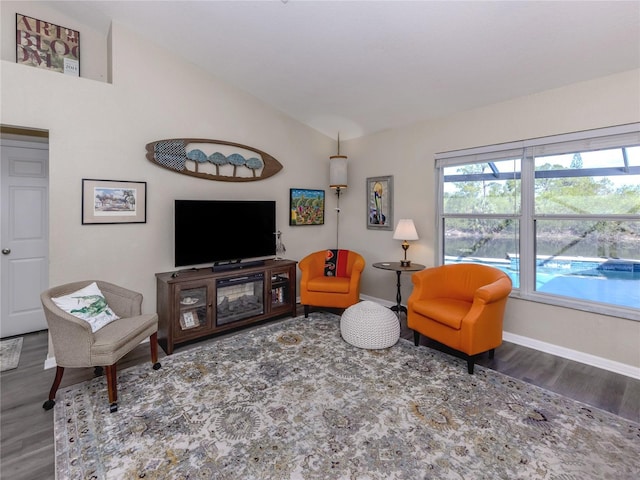 living area featuring lofted ceiling, baseboards, and wood finished floors