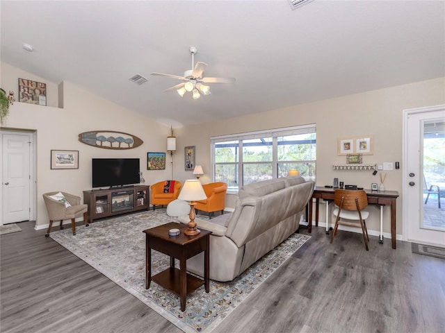 living area featuring visible vents, a ceiling fan, vaulted ceiling, wood finished floors, and baseboards