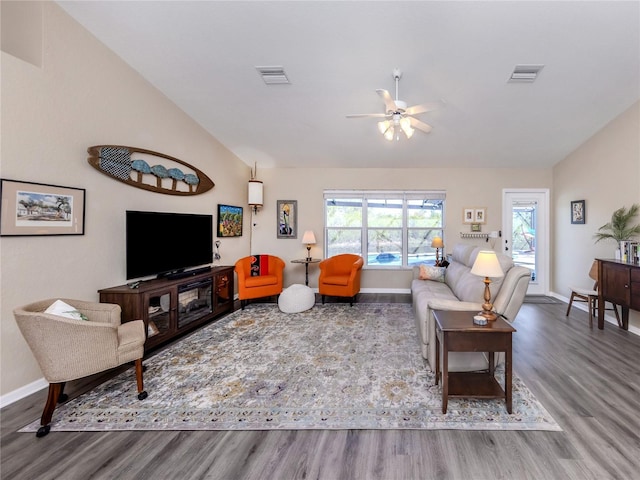 living room with vaulted ceiling, wood finished floors, visible vents, and baseboards